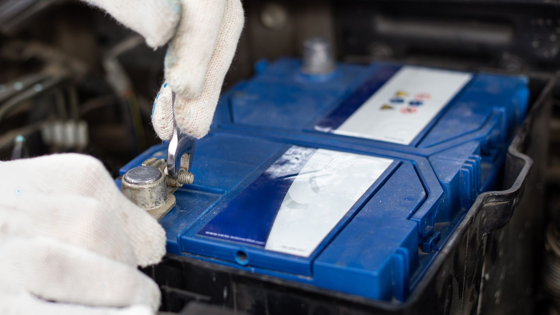 A person in white gloves working on a car battery