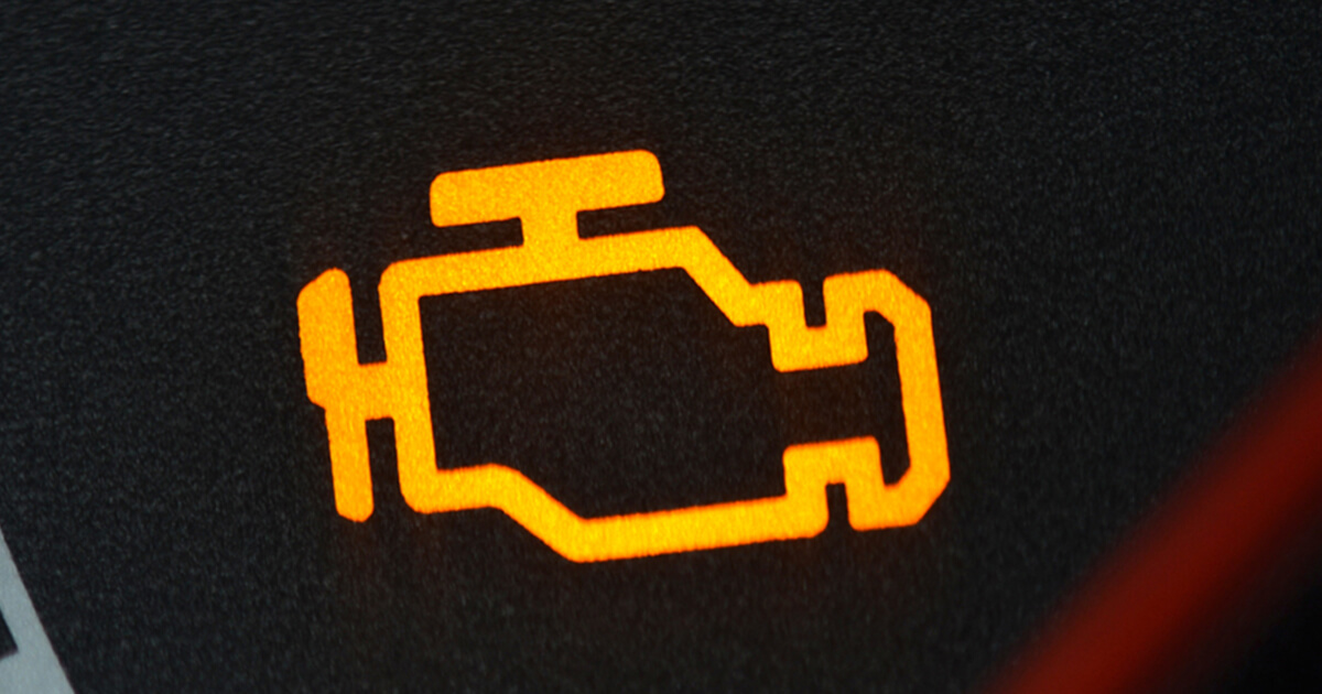Yellow check engine warning light illuminated on car dashboard